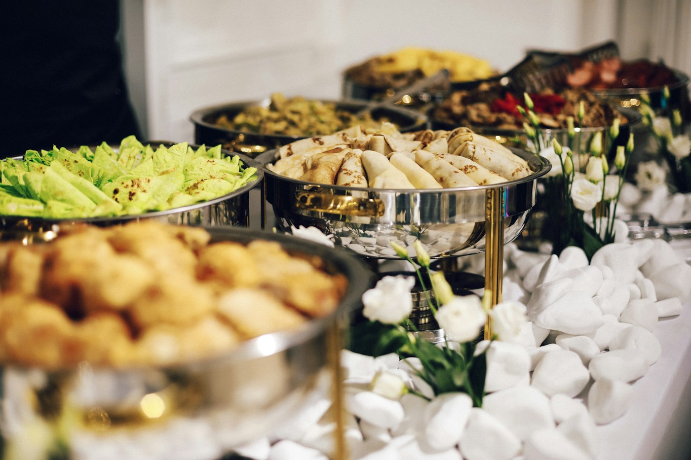 A wedding buffet with silver chafing dishes and fresh flowers