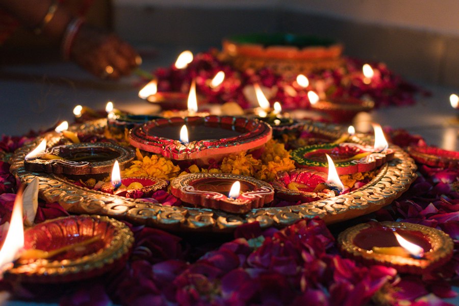 Clay oil lamps glowing among flower petals for a festival